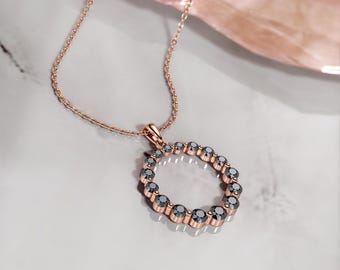 Op de afbeelding: Een ketting van roségoud met een hanger in de vorm van een cirkel van zwarte diamanten.