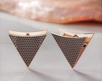May include: A pair of gold triangle earrings with black diamond accents.