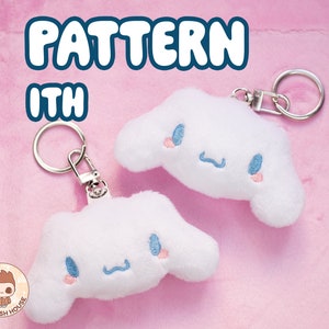 Può includere: Due ciondoli portachiavi in peluche bianca a forma di nuvola con un viso ricamato in blu e rosa. I ciondoli sono attaccati a portachiavi argentati.