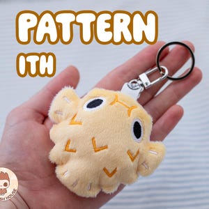 May include: A yellow plush pufferfish keychain with embroidered details. The keychain is attached to a silver key ring. The text "PATTERN ITH" is visible in the image.