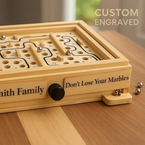 May include: A wooden labyrinth game with a maze design and several metal marbles. The game is engraved with "The Smith Family" and "Don't Lose Your Marbles." The top is a maze with numbered holes and black lines. The words "Custom Engraved" are also visible.