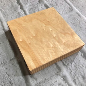 May include: A natural wood box with a light brown finish. The box is made of plywood and has a simple, rectangular shape.