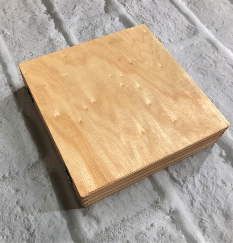 May include: A natural wood box with a light brown finish. The box is made of plywood and has a simple, rectangular shape.