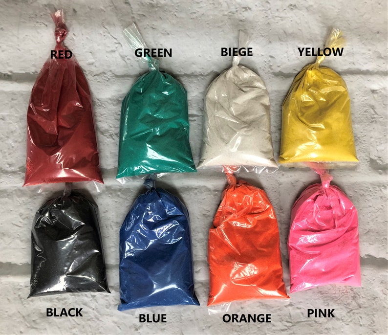 May include: Ten small plastic bags filled with different colored sand. The bags are labeled with the colors: red, green, beige, yellow, black, blue, orange, and pink.