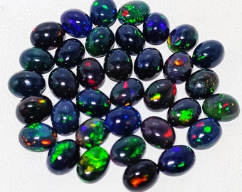 May include: A collection of oval-shaped black opals with iridescent green, blue, and red flashes. The opals are arranged in a loose circle on a white background.