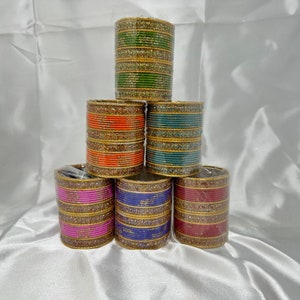 May include: A stack of six colorful bangles with gold accents. The bangles are made of plastic and have a shiny finish.