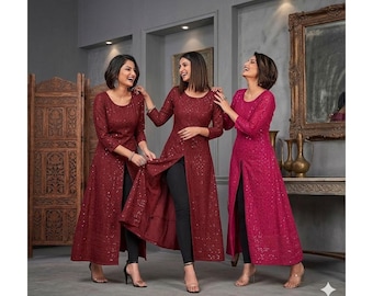May include: Three women wearing long, sequined dresses with a high slit. The dresses are in shades of burgundy and fuchsia, paired with black leggings. The women are smiling and laughing, posing in front of a decorative screen and mirror.