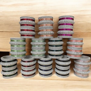 May include: A set of twelve silver bangles with colorful stripes and rhinestones. The bangles are stacked in three rows of four.