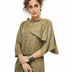May include: Olive green tunic top with a plaid pattern and gold-colored circular buttons. The top has a unique asymmetrical design and three-quarter sleeves. The image also includes the text "PROGRESSIVELY INDIAN".