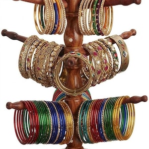 May include: A wooden bangle stand displaying a variety of colorful bangles. The stand is made of dark wood and features multiple arms to hold the bangles. The bangles are in various colors, including gold, red, green, and blue.