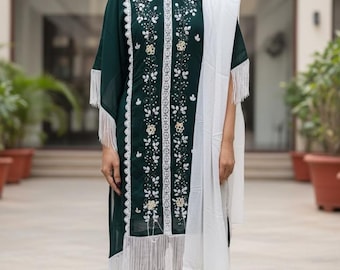 May include: A dark green tunic and white pants ensemble with intricate white floral embroidery. The tunic features fringe detailing on the sleeves and hem. A white scarf is draped over the shoulder. The outfit is completed with matching white pants.