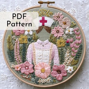 May include: Embroidered hoop art featuring a nurse's uniform and cap surrounded by colorful flowers. The text "PDF Pattern" is overlaid on the image. The embroidery is in shades of pink, green, yellow, and white, set in a wooden hoop.