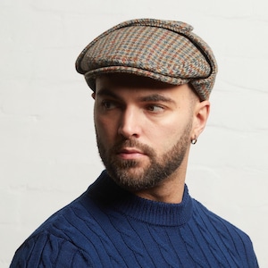 Puede incluir: Gorra plana de tweed en tonos marrón, azul y naranja. La gorra tiene un diseño clásico con una corona redondeada y una pequeña visera rígida. El sombrero está hecho de una tela texturizada y es adecuado para climas fríos.