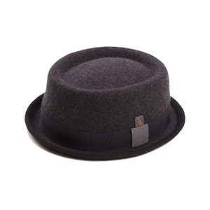 May include: A gray wool flat cap with a black band and a small brown leather logo.