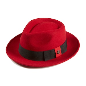 Könnte beinhalten: Ein roter Fedora-Hut mit einem schwarzen Band und einem roten Knopf mit einem braunen Buchstaben D darauf.