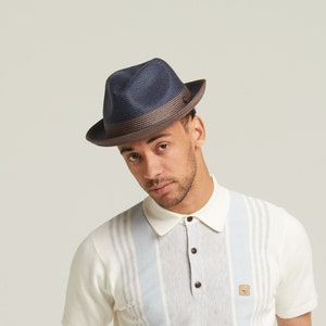 May include: A navy blue and brown fedora hat with a wide brim. The hat has a small button on the top.