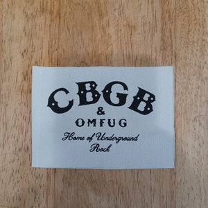 May include: White fabric patch with black text that reads "CBGB & OMFUG Home of Underground Rock".