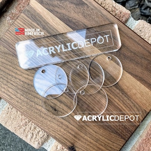 May include: A close-up of a wooden surface with a clear acrylic sign that reads "ACRYLICDEPOT" and "Made in America". There are several clear acrylic circles with holes on the surface.