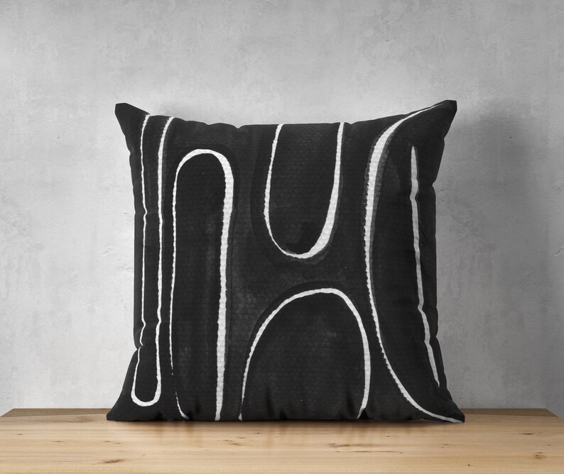 May include: Black and white throw pillow with an abstract design of white lines on a black background.