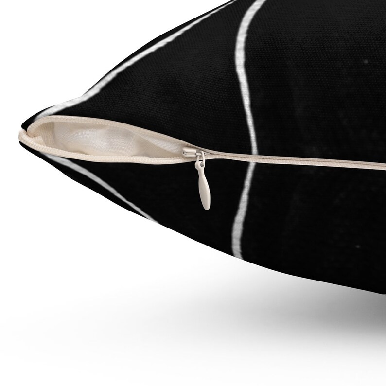 May include: A black and white throw pillow with a geometric pattern. The pillow has a zipper closure.
