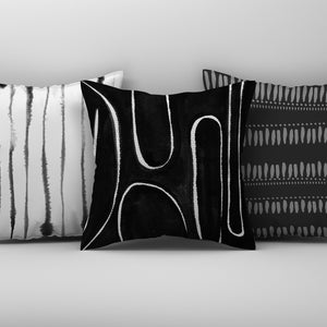 May include: Three black and white throw pillows with abstract geometric patterns. The pillows are arranged in a row on a white surface.