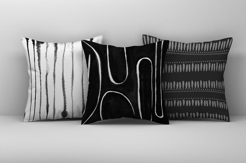 May include: Three black and white throw pillows with abstract geometric patterns. The pillows are arranged in a row on a white surface.