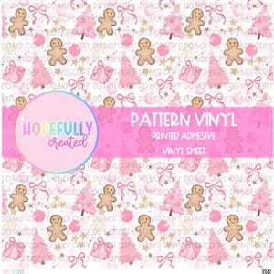 May include: A sheet of pattern vinyl featuring a repeating design of gingerbread men, Christmas trees, gifts, bows, and ornaments in pink and gold on a white background. The text "PATTERN VINYL" is displayed.