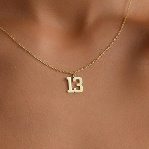 May include: A gold chain necklace with a pendant featuring the number "13" in a bold, blocky font.