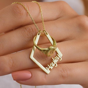 May include: Gold necklace with a diamond-shaped pendant featuring the name "Hayley" and a ring charm.