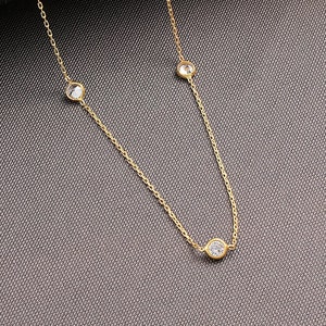 May include: A gold chain necklace with five clear round stones.