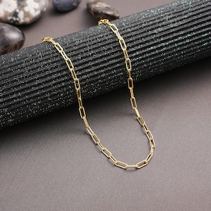 May include: A gold chain necklace with a delicate, linked chain design. The chain is made of small, rectangular links.