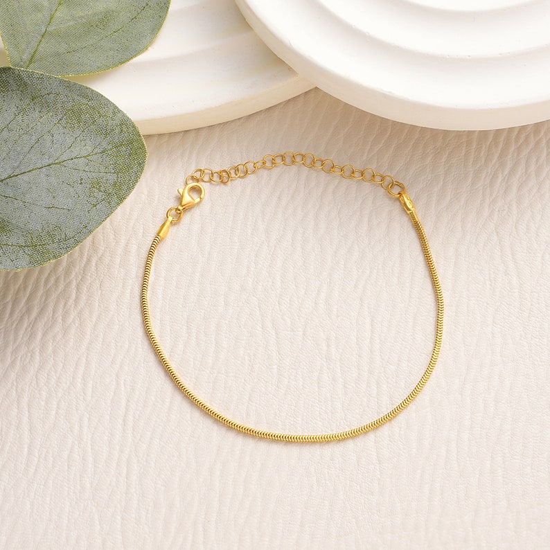 May include: A gold snake chain bracelet with a lobster clasp.