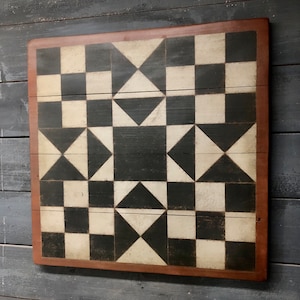 May include: Black and white geometric pattern painted on a wooden board with a brown frame. The pattern is made up of squares and triangles.