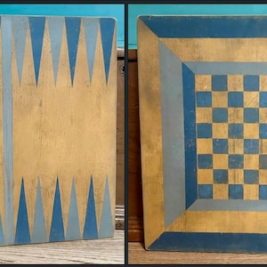 May include: A dual-sided wooden game board featuring a backgammon layout with alternating light and dark blue triangles on a natural wood background on one side, and a blue and natural wood checkerboard pattern on the reverse side.
