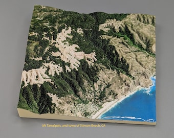 Könnte beinhalten: Eine Luftaufnahme des Mount Tamalpais und der Stadt Stinson Beach, Kalifornien. Das Bild zeigt eine Berglandschaft mit grünen Bäumen und einem Sandstrand mit blauem Wasser.