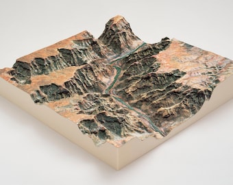 May include: A detailed 3D model of a canyon with a river running through it. The model is made of a light brown material and has a textured surface. The canyon walls are steep and rocky, and the river is narrow and winding.