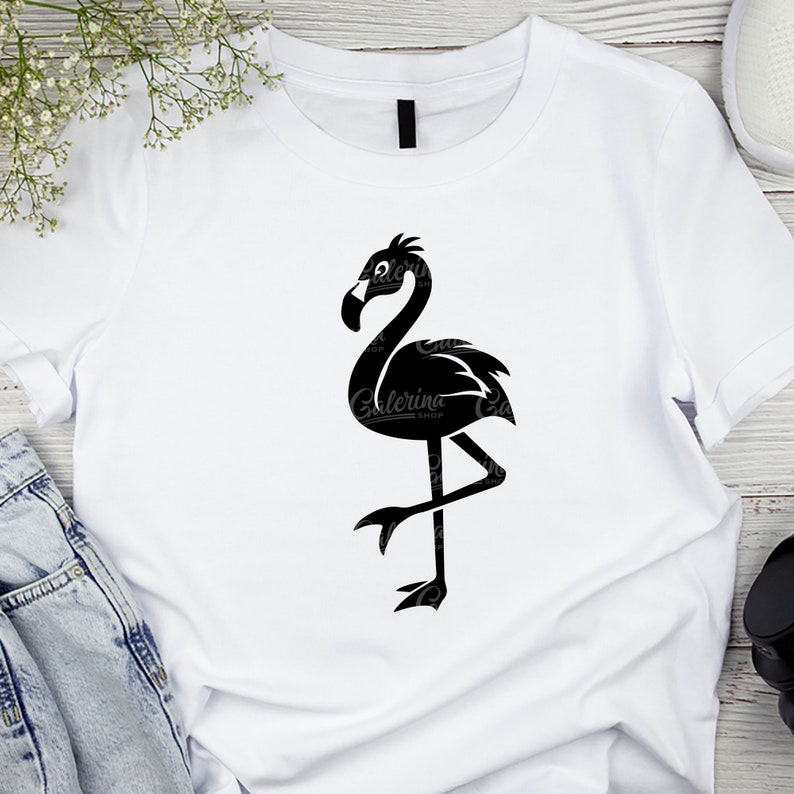 May include: A white t-shirt with a black silhouette of a flamingo standing on one leg.