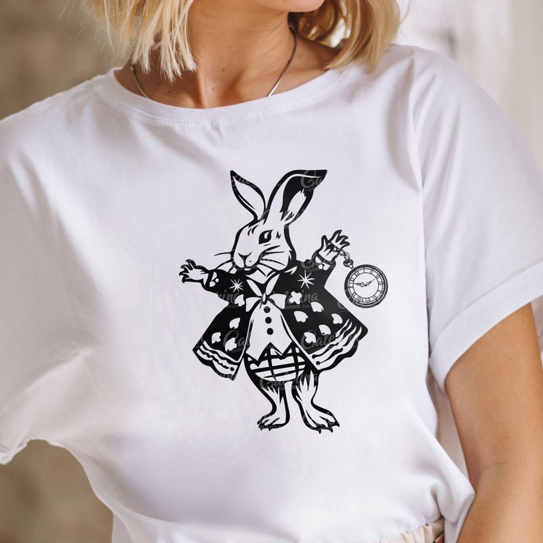 May include: White t-shirt with a black and white illustration of the White Rabbit from Alice in Wonderland holding a pocket watch.
