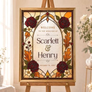 May include: A rectangular wedding sign in a gold frame featuring a stained glass design with red roses, orange oak leaves, and white flowers. The center text reads: WELCOME TO THE WEDDIGN OF Scarlett & Henry OCTOBER 12, 2027, set on a textured background.