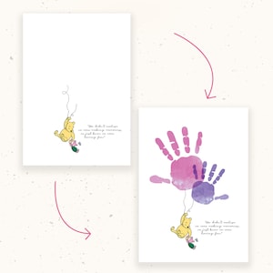 May include: Two white art prints. One features a yellow Winnie the Pooh and Piglet illustration hanging from a string. The other print shows two overlapping handprints in pink and purple watercolor. Text: "We didn't realize we were making memories, we just knew we were having fun!"