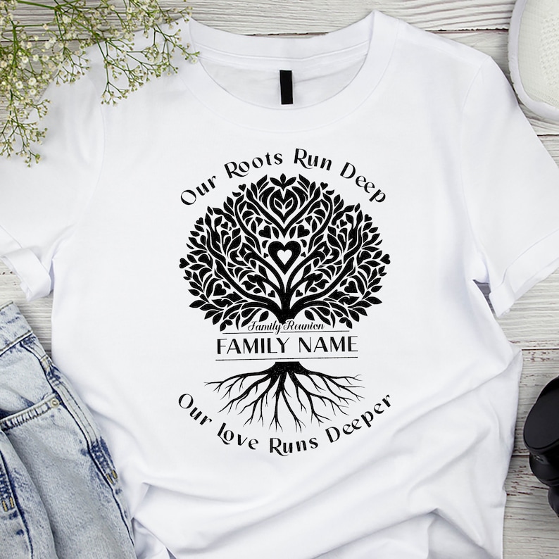 May include: White t-shirt with a black family tree design. The tree has a heart in the center and the text "Our Roots Run Deep" and "Our Love Runs Deeper" around it. The text "Family Reunion FAMILY NAME" is at the base of the tree.