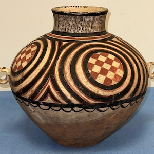 May include: A large, round, brown ceramic pot with two handles. The pot is decorated with black and red geometric patterns, including circles, squares, and stripes.
