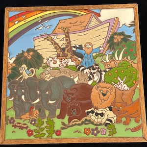 May include: A colorful ceramic tile depicting Noah's Ark with a rainbow above. The ark is filled with animals, including elephants, giraffes, lions, and bears. Noah is standing on the ark, waving to the animals.