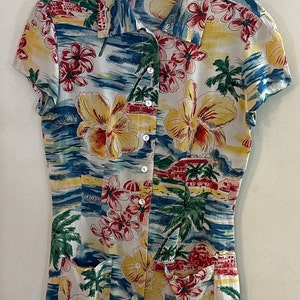 May include: A short-sleeved button-down shirt with a tropical print featuring red and yellow flowers, palm trees, and coastal scenes. The shirt has a collared neckline and a fitted silhouette. The label reads "LIMITED america".