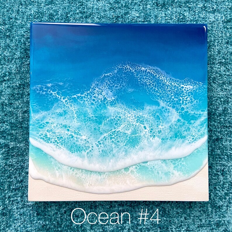May include: Square artwork depicting an ocean scene. The image features a gradient of blues, from deep navy to light turquoise, representing the water. White foamy waves crash onto a sandy beach. The text "Ocean #4" is at the bottom.