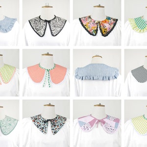May include: A collection of 10 different fabric collars in various patterns and colors, including gingham, floral, and animal print. The collars are all attached to white shirts with ruffled edges.