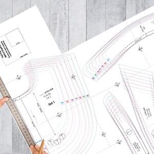 K&ouml;nnte beinhalten: Ein Schnittmuster f&uuml;r ein Kleid mit mehreren Gr&ouml;&szlig;en und Anweisungen. Das Muster ist auf wei&szlig;em Papier mit schwarzen Linien und Text gedruckt. Der Text enth&auml;lt "Atelier", "Front BD", "Cut 2" und "Set 1".