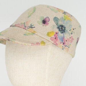 Pode incluir: Um bon&eacute; de lona bege com estampa floral com flores de aquarela rosa, azul e amarela.