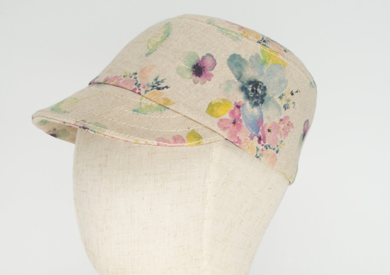 Pode incluir: Um bon&eacute; de lona bege com estampa floral com flores de aquarela rosa, azul e amarela.