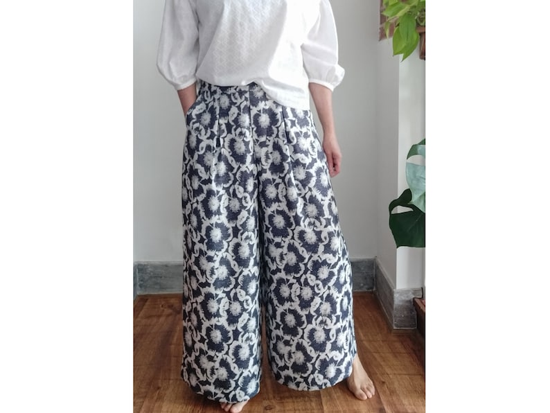 May include: Wide-leg pants with a black and white floral print. The pants have a high waist and are made of a lightweight fabric.